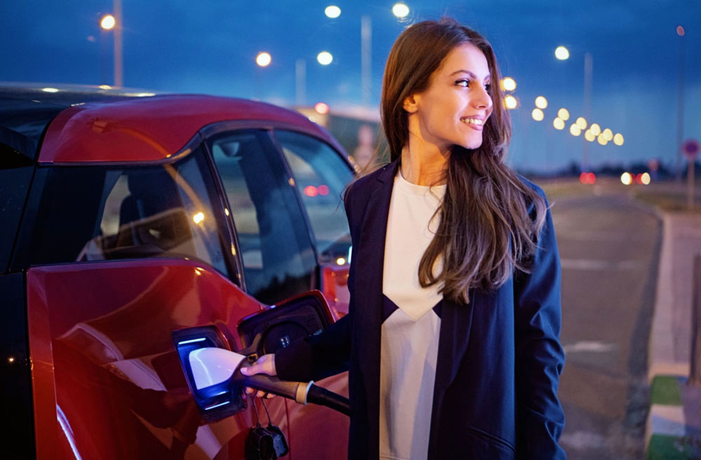 Ragazza Ricarica l Auto Elettrica di Sera Ragazza Ricarica l Auto Elettrica di Sera